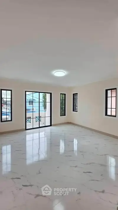 Spacious and bright living room with large windows and marble flooring in modern home.
