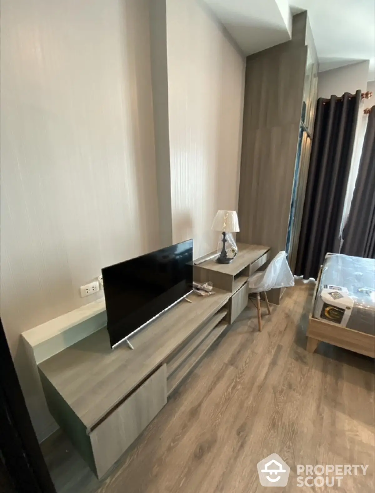 Modern bedroom with stylish furniture and TV unit, featuring elegant wood flooring and natural light.