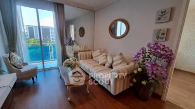 Charming living room with elegant decor and balcony view, featuring cozy seating and vibrant floral accents.