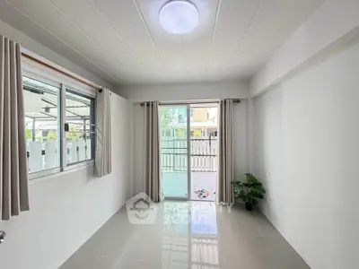 Bright empty room with large windows and sliding glass door leading to patio.