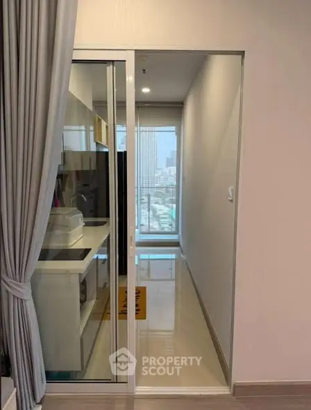 Modern apartment hallway with sliding glass door and city view.