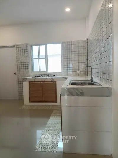 Modern kitchen with sleek design and tiled backsplash, featuring a large window for natural light.
