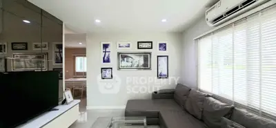 Modern living room with sleek furniture and wall art, featuring a large window with blinds.