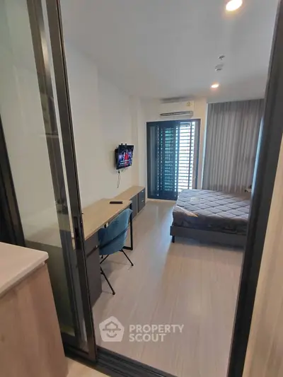 Modern bedroom with sleek design, featuring a wall-mounted TV, desk, and large window for natural light.