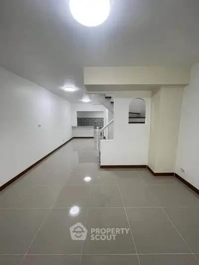 Spacious modern living room with sleek tile flooring and staircase