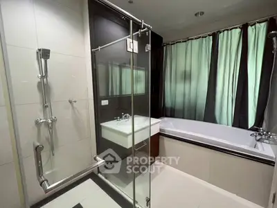 Modern bathroom with glass shower and bathtub, featuring sleek design and natural light.