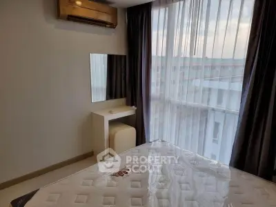 Cozy bedroom with modern air conditioning and natural light from large window.