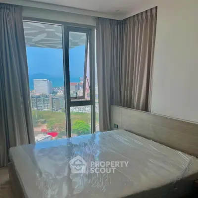 Modern bedroom with stunning city view and floor-to-ceiling windows in high-rise apartment.