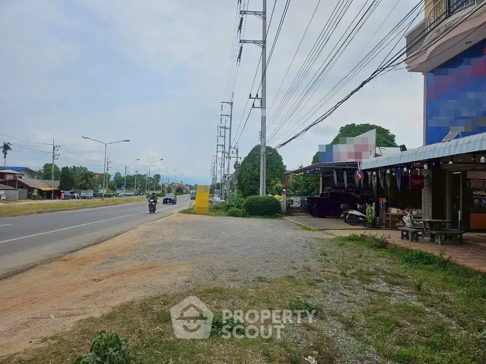 Roadside view with commercial building and open space, ideal for business opportunities.