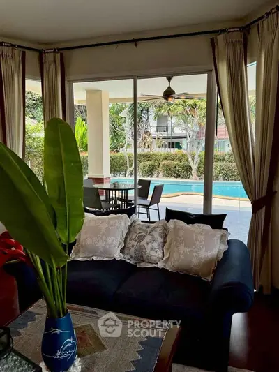 Luxurious living room with pool view, elegant curtains, and cozy sofa in a serene setting.