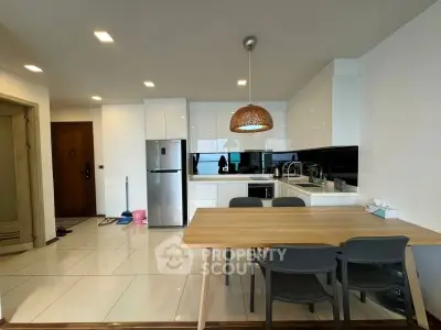 Modern kitchen with sleek white cabinets and dining area in open layout apartment.