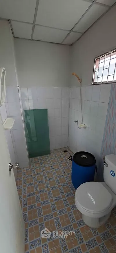 Compact bathroom with tiled floor and basic fixtures, ideal for budget-friendly living spaces.