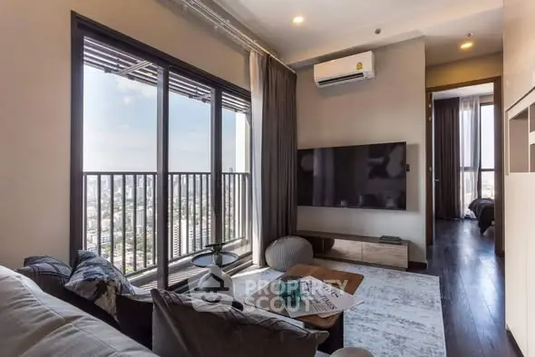 Modern living room with large windows offering stunning city views, stylish decor, and cozy seating area.
