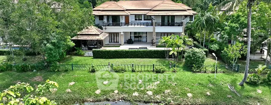 Luxurious villa with lush garden and serene water view, perfect for tranquil living.