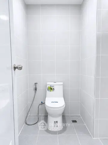 Modern bathroom with sleek white tiles and contemporary toilet design.