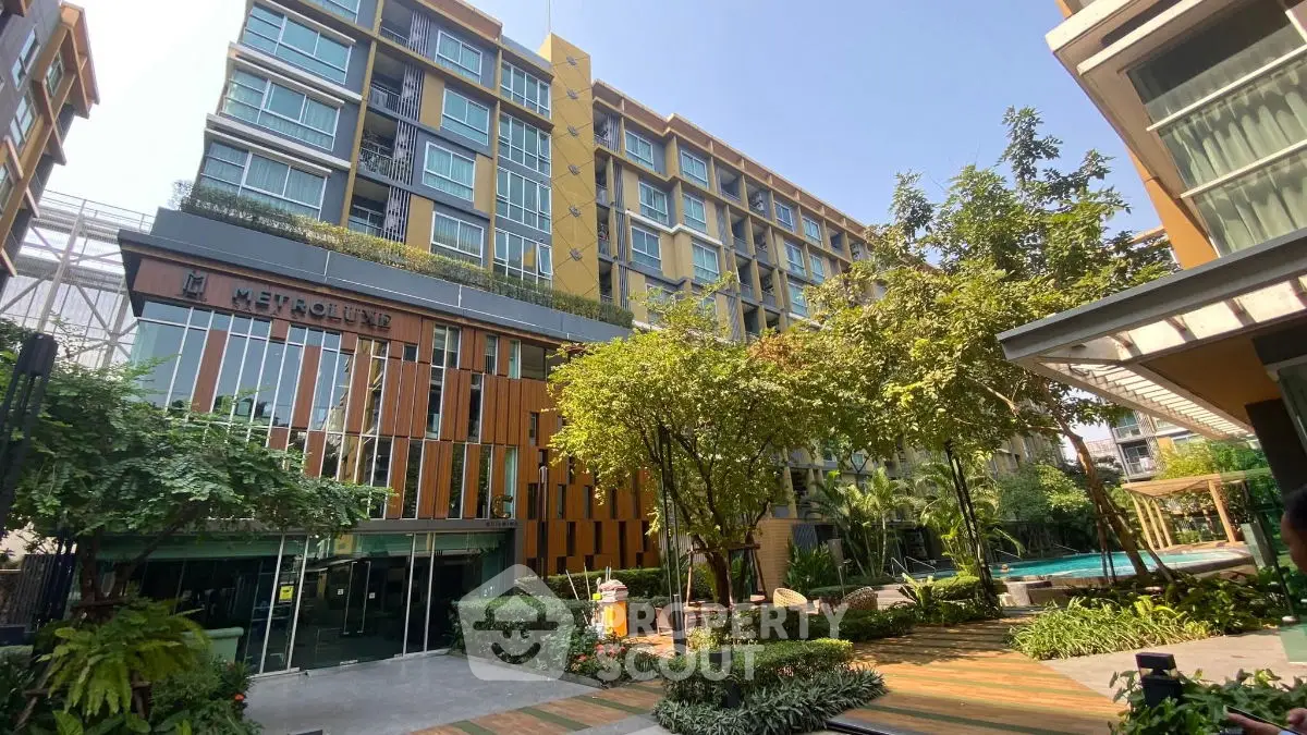 Modern condominium building with lush garden and pool area, perfect for urban living.