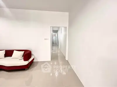 Minimalist living room with sleek white walls and modern red sofa
