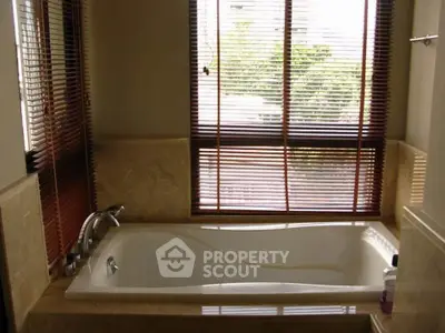 Luxurious bathroom with large bathtub and window blinds