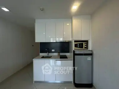 Modern compact kitchen with sleek white cabinetry and stainless steel appliances.