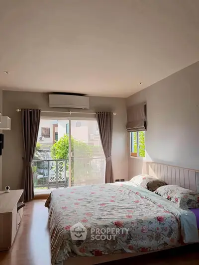 Spacious bedroom with floral bedding and large window offering natural light and garden view.