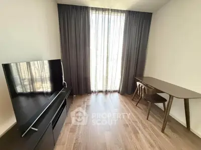 Modern living room with wooden flooring, TV, and study desk near large window with curtains.