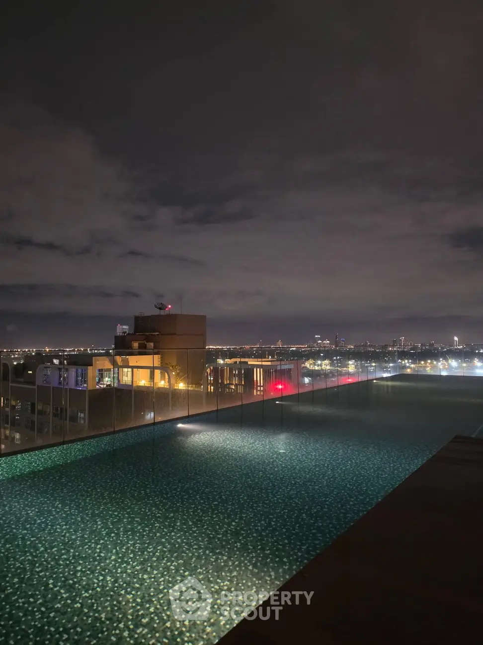Stunning rooftop pool with breathtaking city skyline view at night, perfect for luxury living.