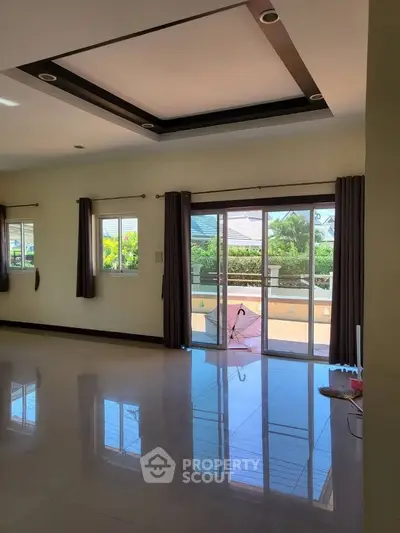 Spacious living room with large windows and balcony access, perfect for natural light.