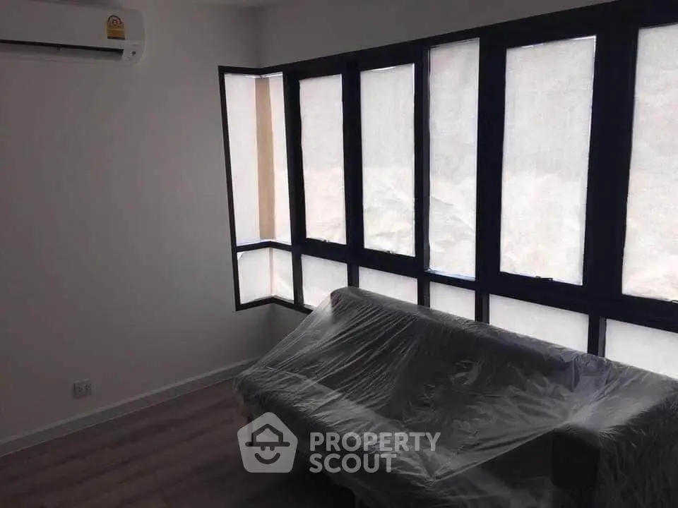 Modern living room with large windows and sleek air conditioning unit.