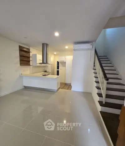 Modern open-plan kitchen with sleek design and staircase in contemporary home