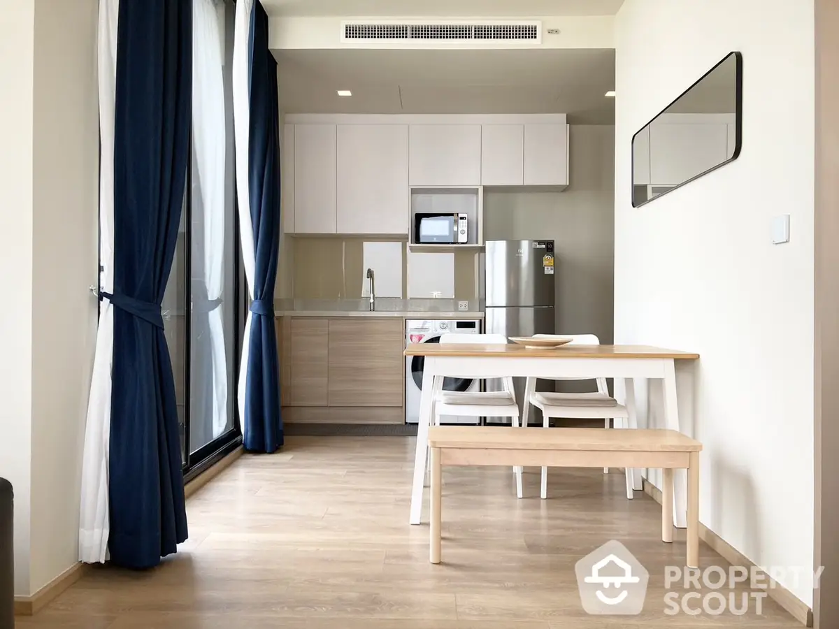 Modern minimalist studio apartment with open kitchen layout, sleek cabinetry, and ample natural light, perfect for urban living.