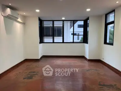 Spacious empty room with large windows and wooden flooring