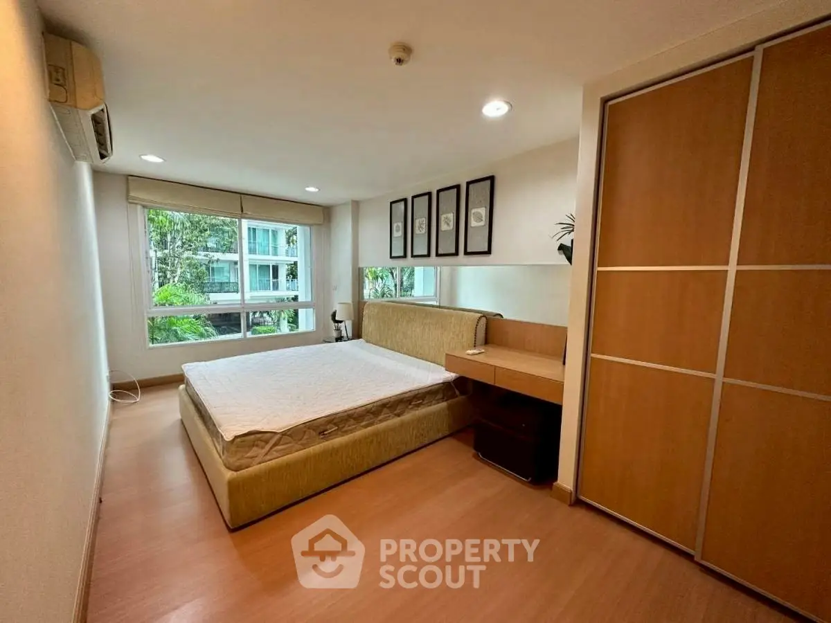 Spacious bedroom with large window and modern decor in a serene setting.