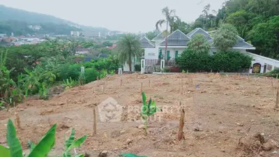 Scenic land plot with lush greenery and distant view of residential area.