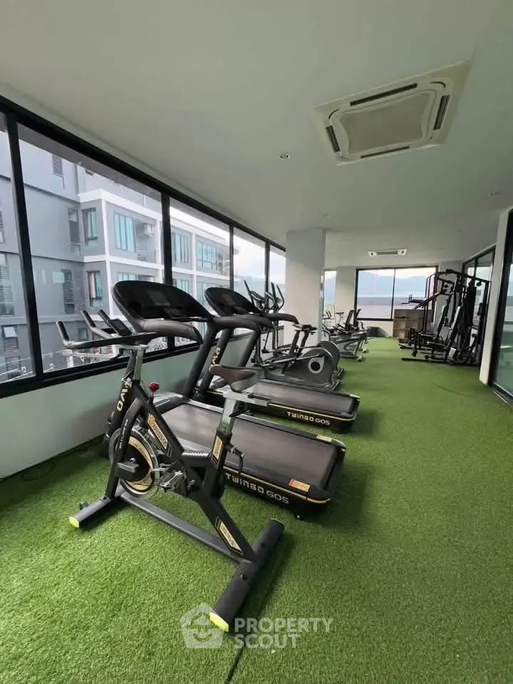 Modern gym with state-of-the-art equipment and large windows offering a bright and airy workout space.
