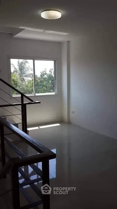 Bright and airy room with large window and staircase, perfect for modern living.