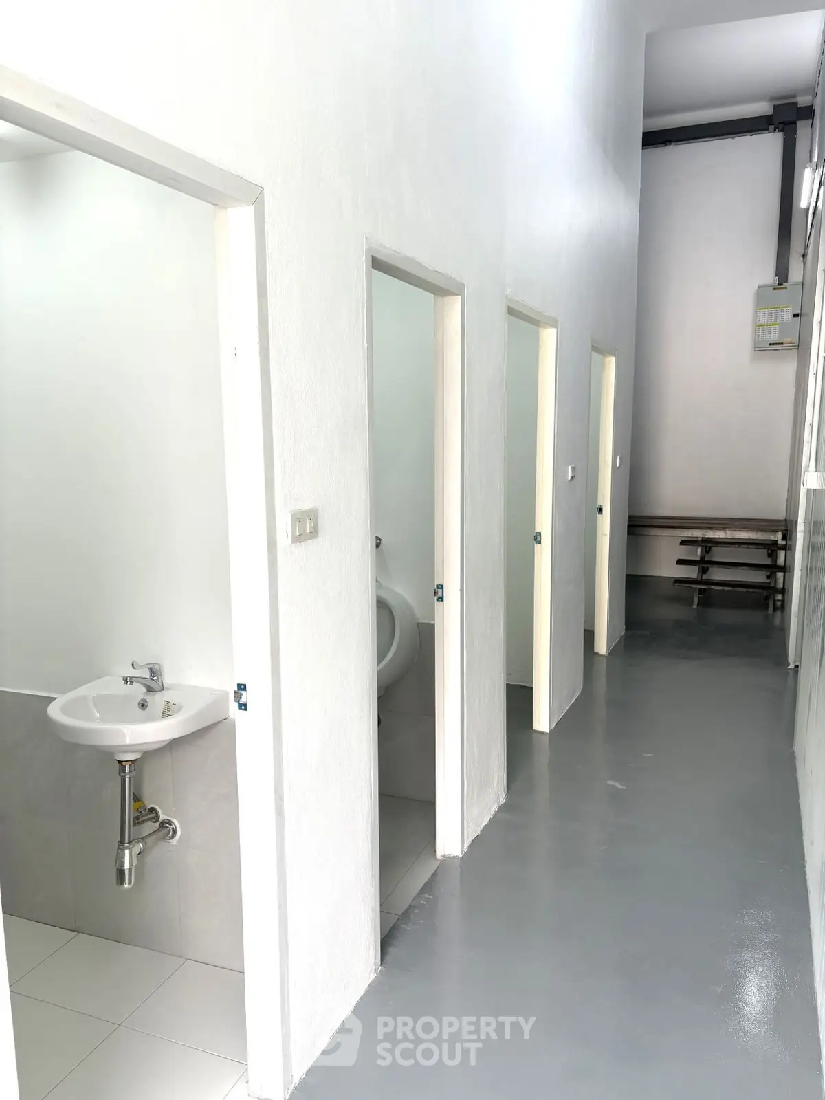 Modern communal bathroom with sleek design and multiple stalls in a bright, clean space.