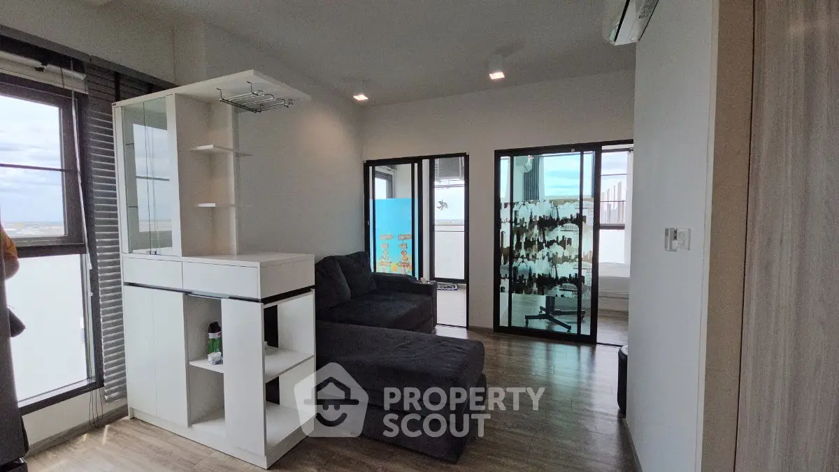 Modern living room with sectional sofa and large windows offering natural light.
