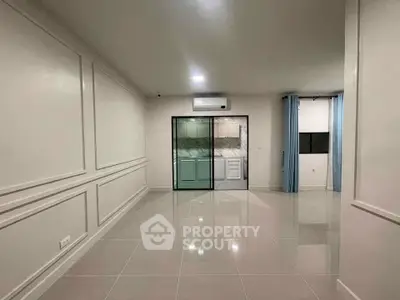 Spacious modern living room with sleek tile flooring and glass partition leading to kitchen.