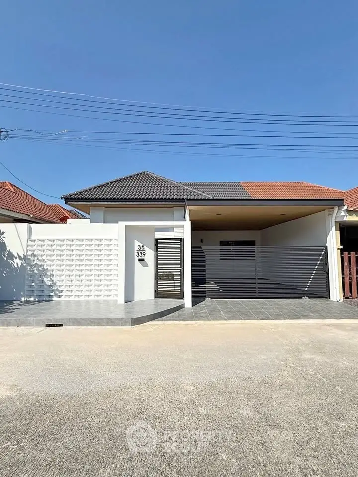 Modern single-story house with sleek design and spacious driveway under clear blue sky.