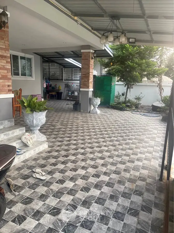 Spacious covered patio with stylish tiled flooring and garden view, perfect for outdoor relaxation.