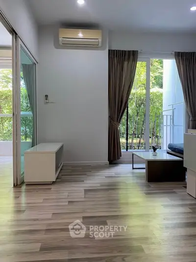 Spacious living room with modern decor and large windows overlooking greenery.