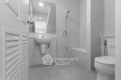 Modern minimalist bathroom with sleek fixtures and neutral tones, featuring a shower and toilet.