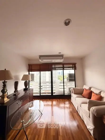 Chic living room with wooden floors, cozy sofa, and city view from large windows.