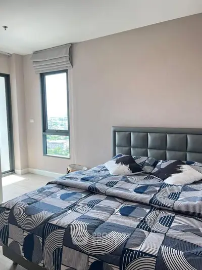 Modern bedroom with stylish decor and large windows offering city views.