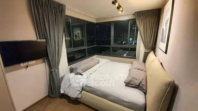 Cozy bedroom with city view, featuring large windows and modern decor.