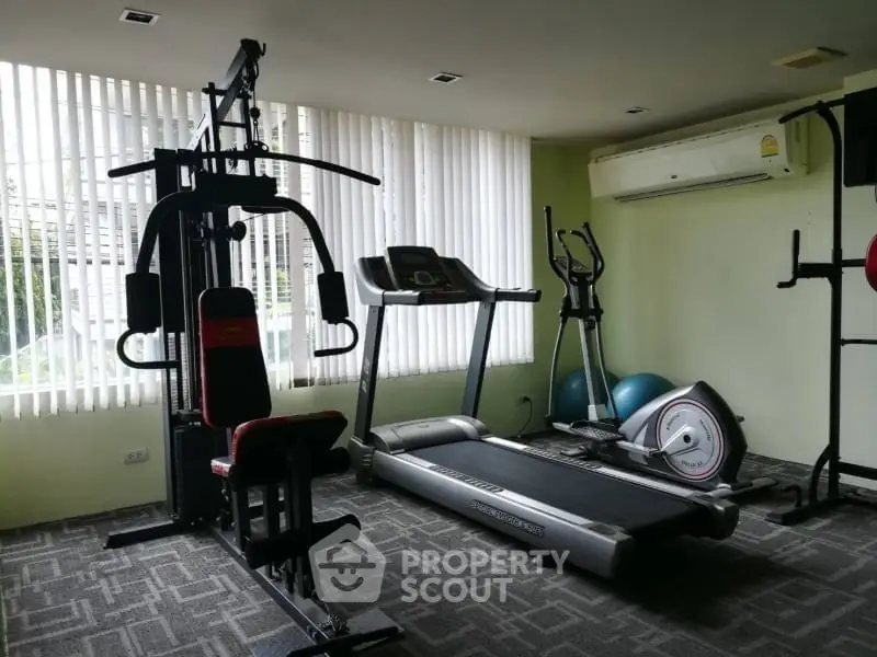 Modern home gym with treadmill and exercise equipment in bright room.