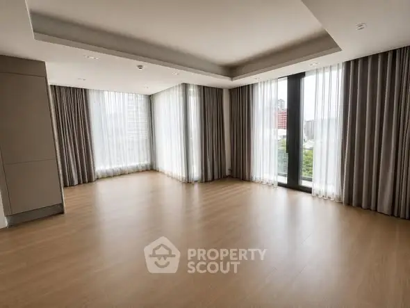 Spacious corner unit with floor-to-ceiling windows and elegant drapery in a modern living room.