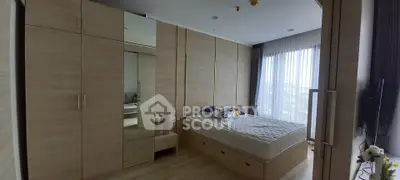 Spacious bedroom with modern wardrobe and large window offering natural light.