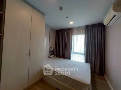 Cozy bedroom with natural light, featuring a comfortable bed and ample storage space.