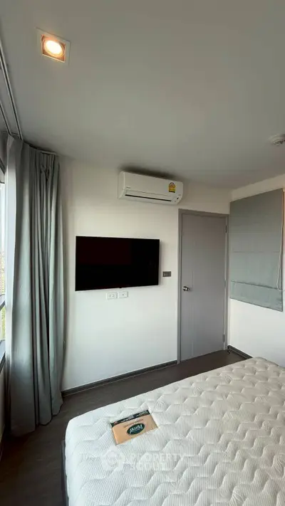 Modern bedroom with air conditioning and wall-mounted TV, featuring a comfortable mattress and elegant curtains.